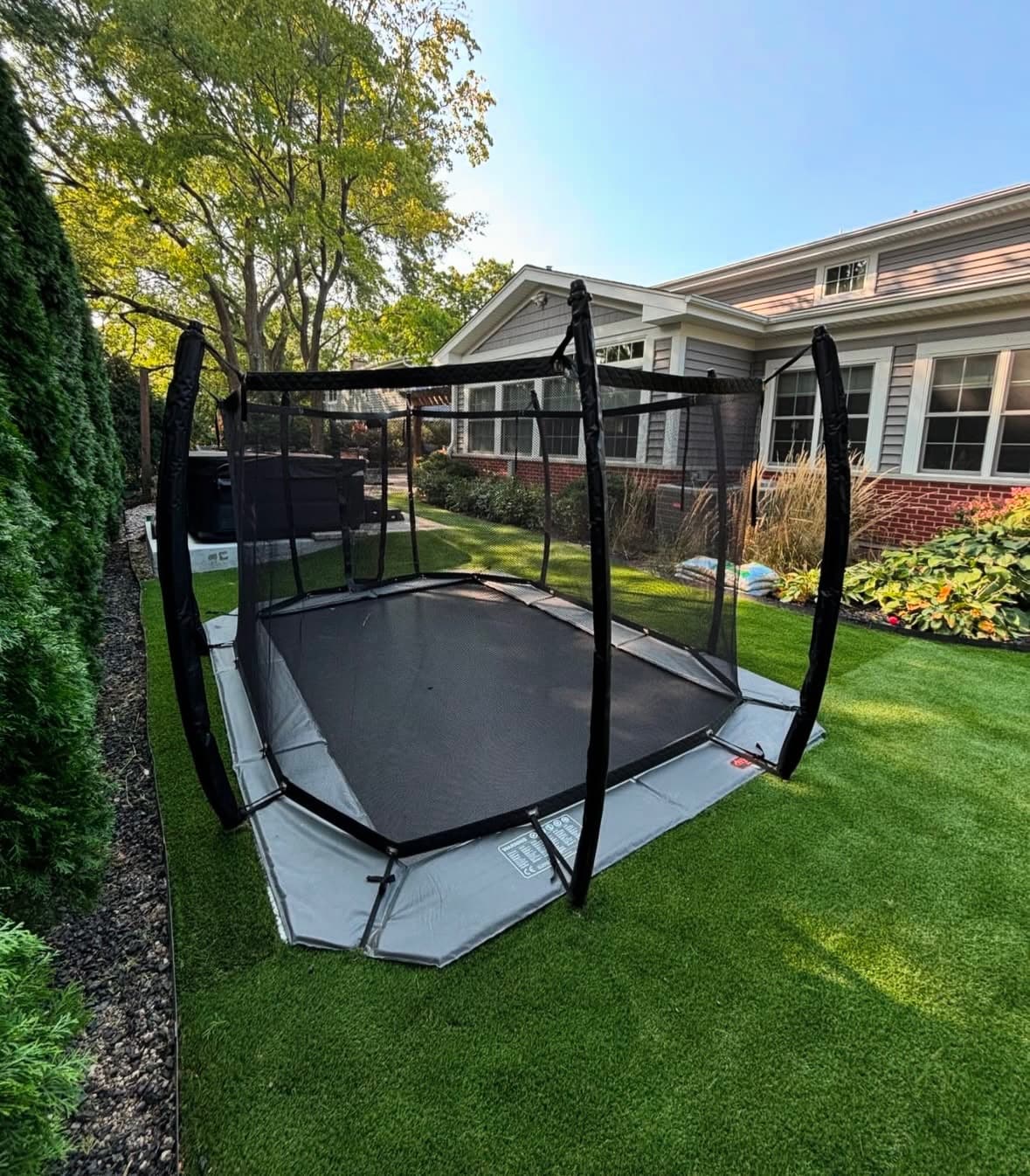 In-ground trampoline flush with artificial turf